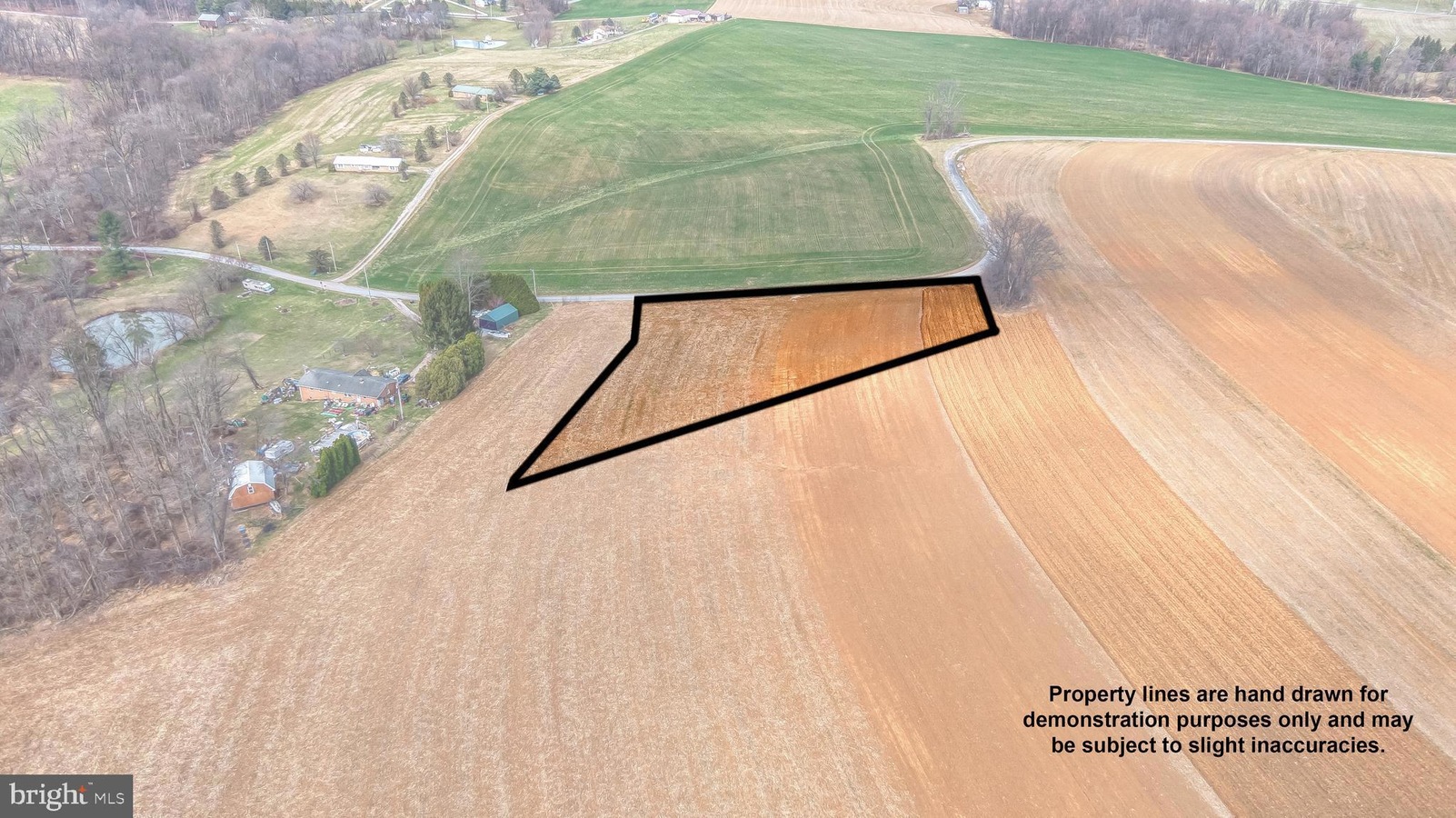 Aerial view of farmland showing a hand-drawn polygon outlining the property boundaries amid fields, roads, and houses.
