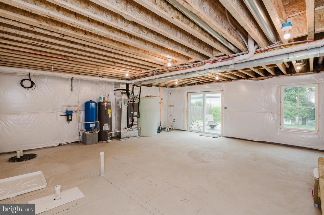 Unfinished basement with exposed ceiling joists, HVAC equipment, water heater, and white plastic vapor barriers along the walls.