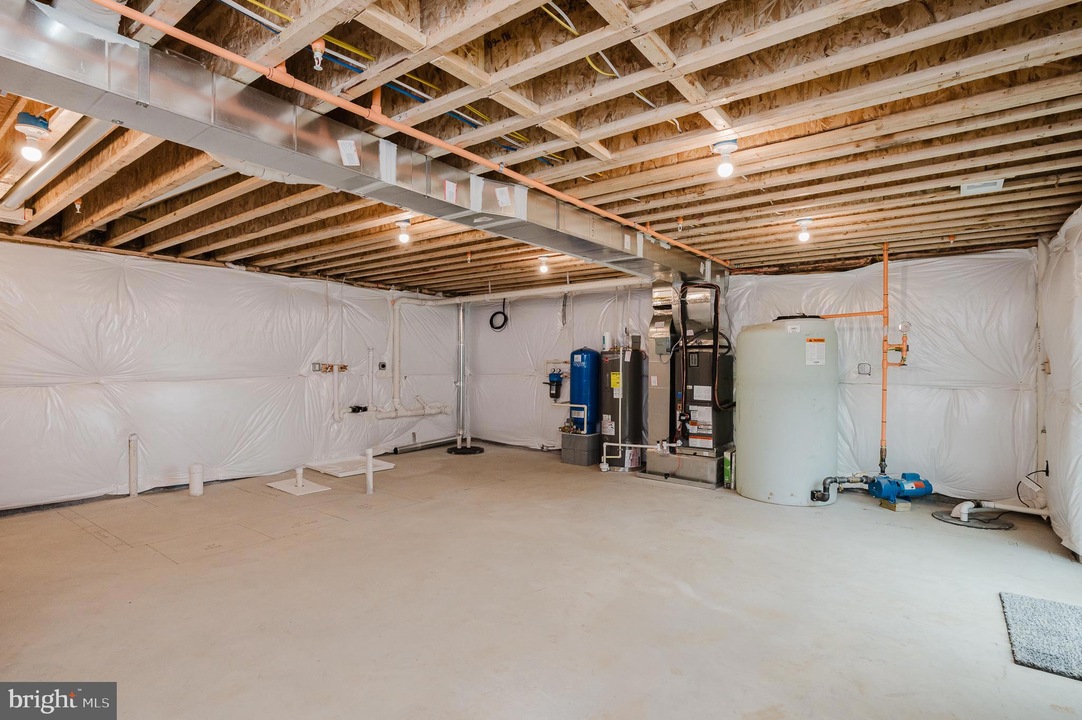 Unfinished basement utility room with exposed joists, ductwork, and HVAC equipment along the back wall.