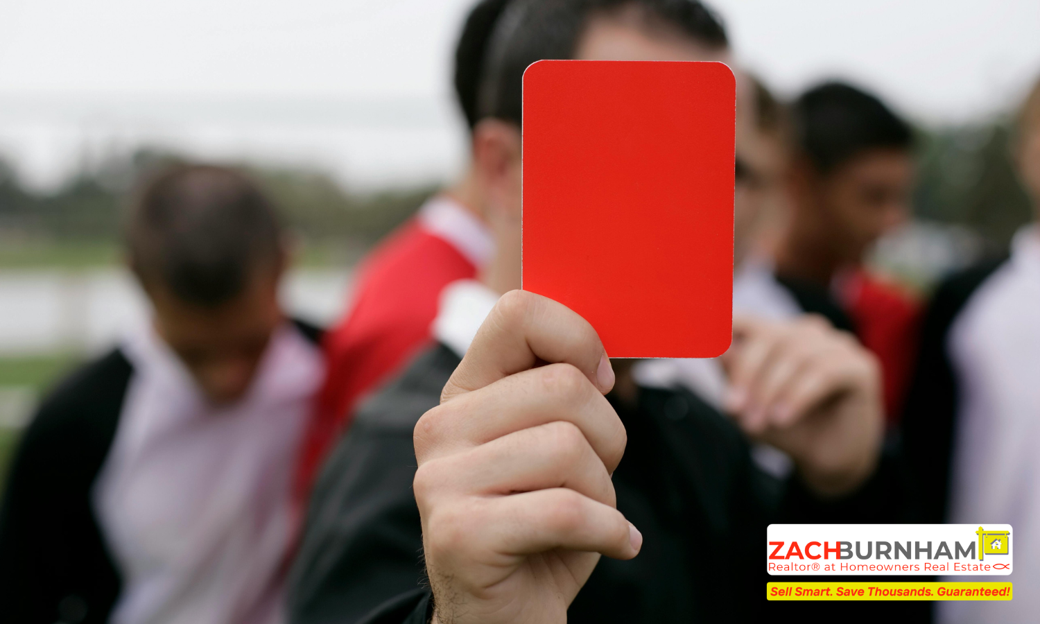 Close-up of a hand holding a bright red card up toward the camera, with blurred people in the background.