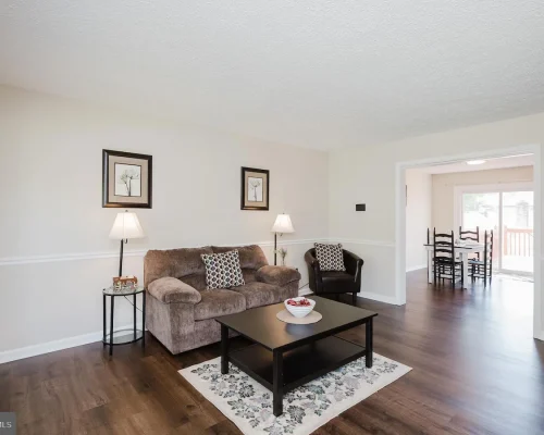 Cozy living room with a brown sofa, matching chair, two lamps, and a black coffee table on a floral rug.