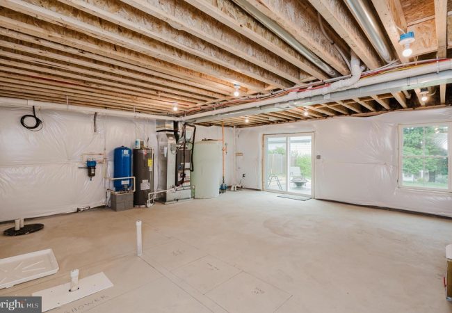 Unfinished basement with exposed ceiling joists, HVAC equipment, water heater, and white plastic vapor barriers along the walls.