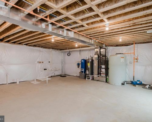 Unfinished basement utility room with exposed joists, ductwork, and HVAC equipment along the back wall.