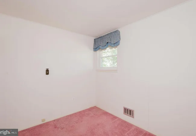 Small empty white room with pink carpet, a single window with blue valance, and a wall vent.