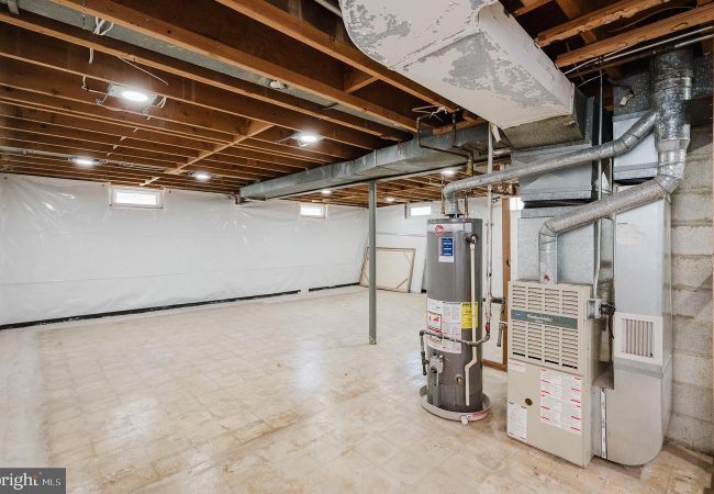 Unfinished basement utility area with exposed ceiling joists, ductwork, and a water heater next to a furnace.